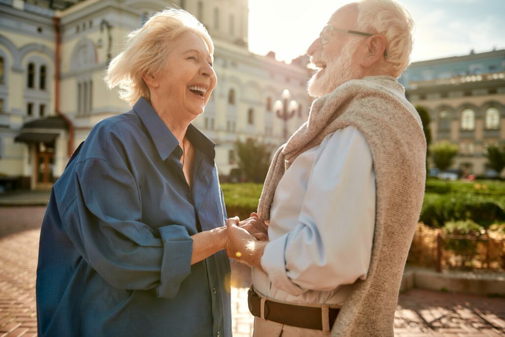 So wonderful day! Happy and beautiful elderly couple holding hands and laughing while standing